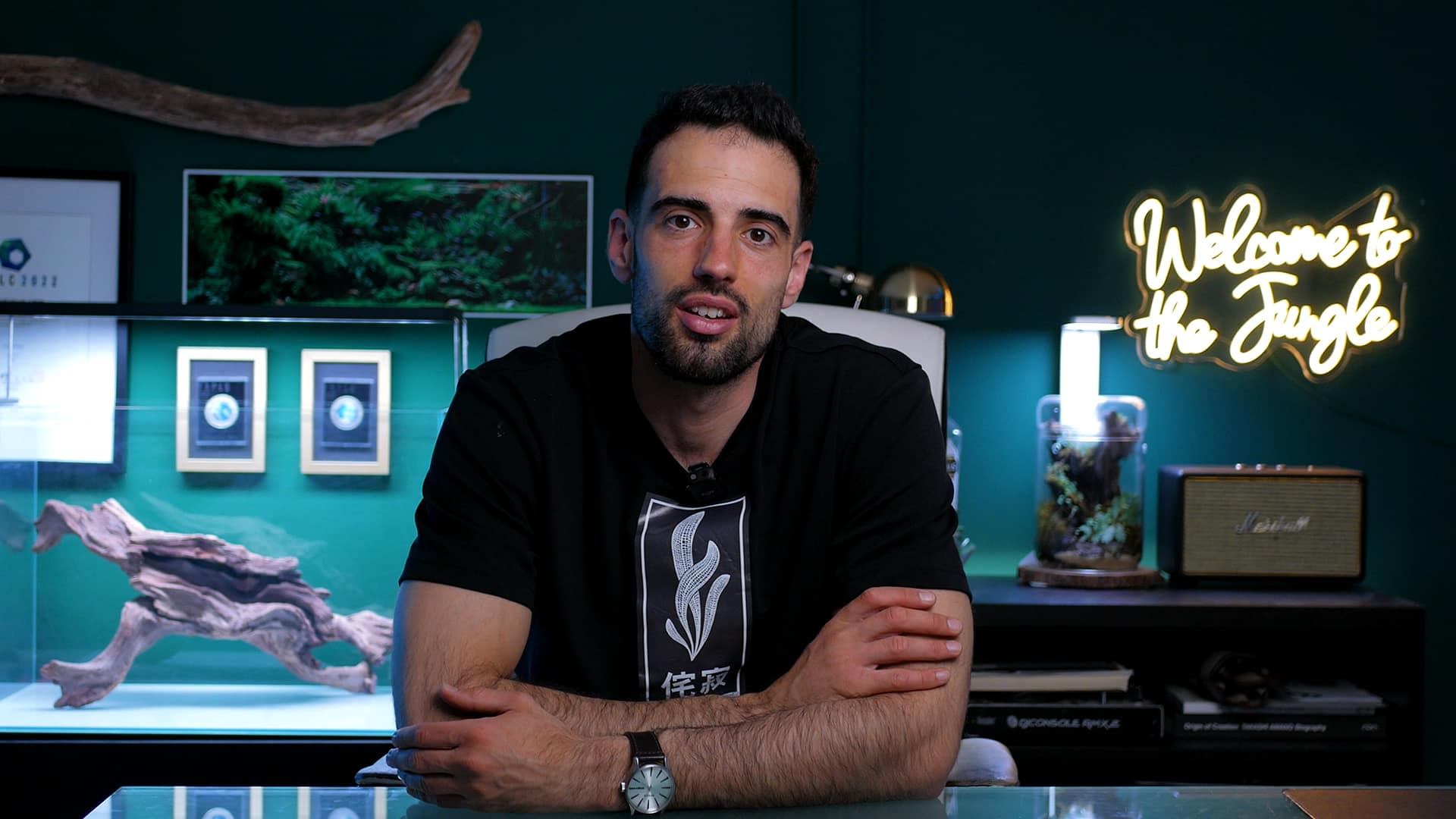 João Pinheiro sentado em estúdio verde-escuro com néon Welcome to the Jungle